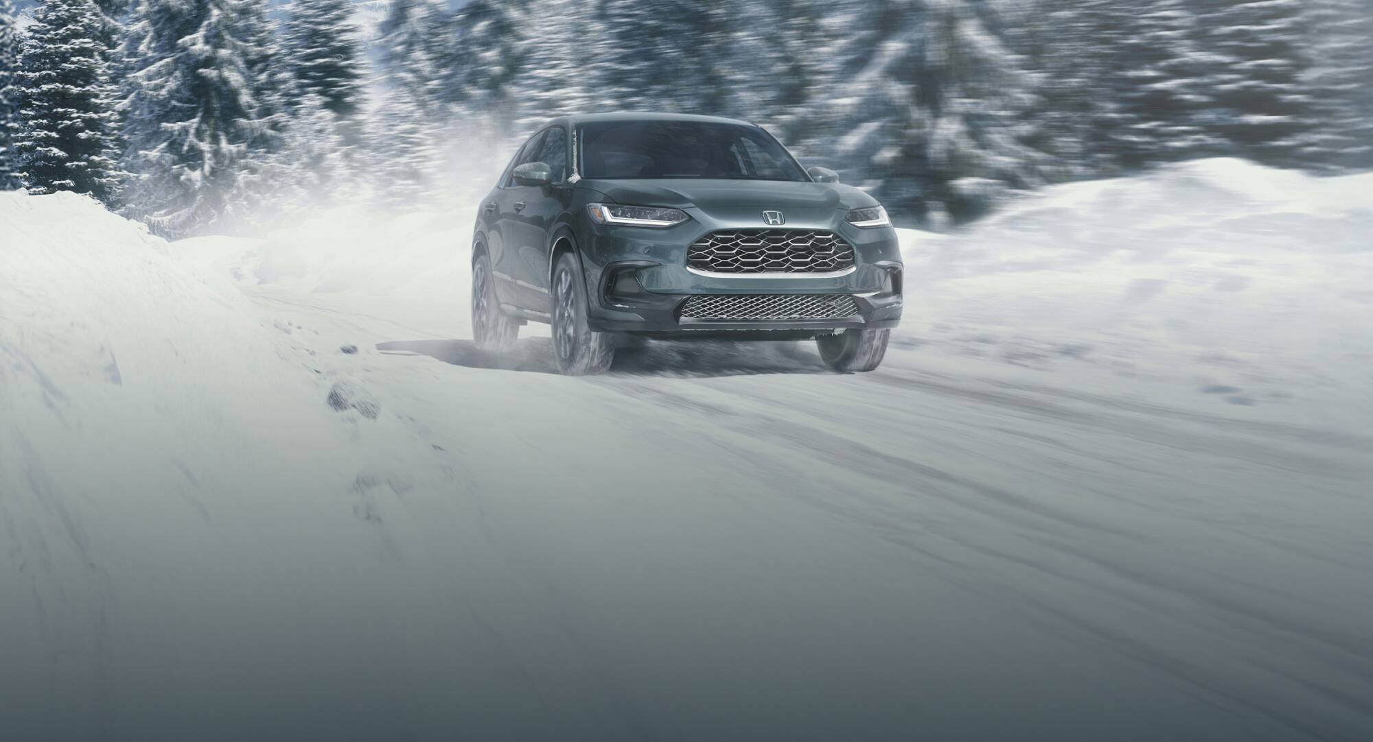 2027 Honda HR-V EX-L in Nordic Forest Pearl front view driving on a snowy road (Subcompact Crossover SUV).